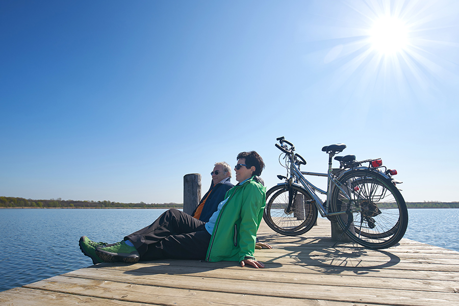 Senioren Paar mit Fahrrädern am Holzsteg über dem See