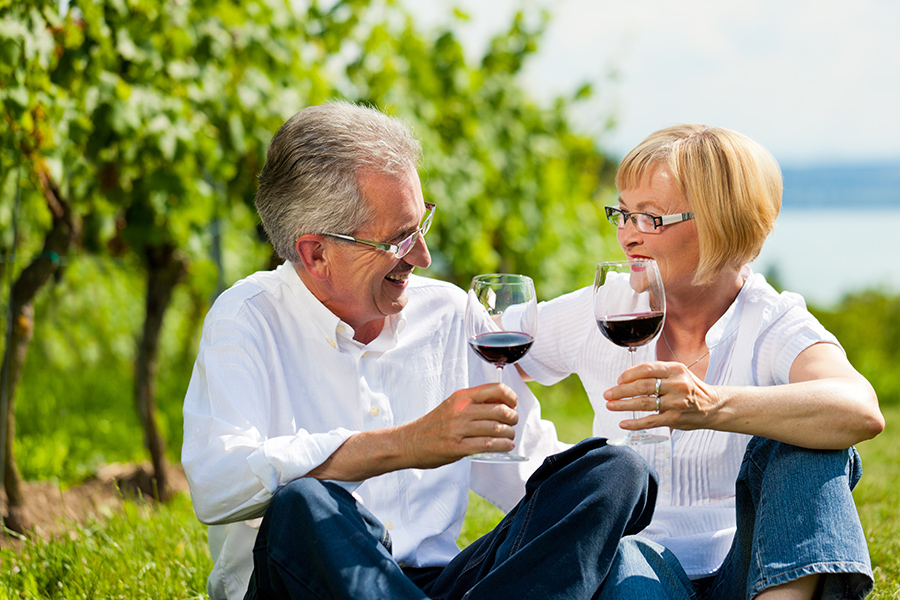 Senioren Paar prostet sich mit Rotweingläsern im Weingarten zu